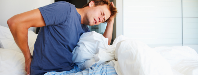 Hombre adulto con dolor lumbar al levantarse de la cama.
