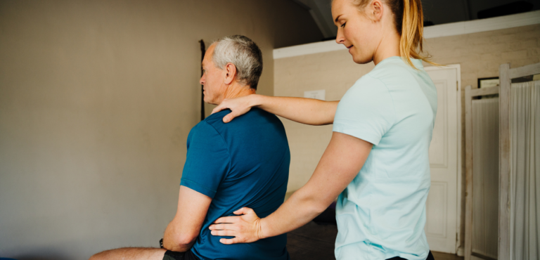 Fisioterapeuta realizando una valoración a una persona con dolor lumbar.